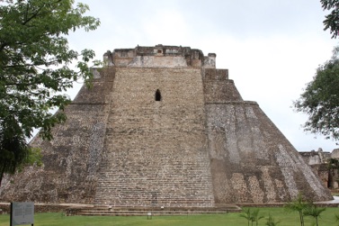 Ancient stone pyramid with steps and greenery.