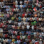 A large group of people sitting in the middle of a crowd.
