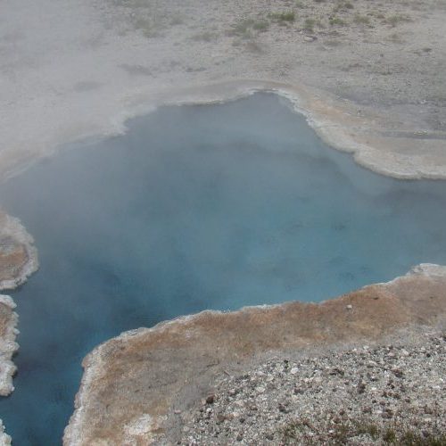 A blue pool of water in the middle of a field.