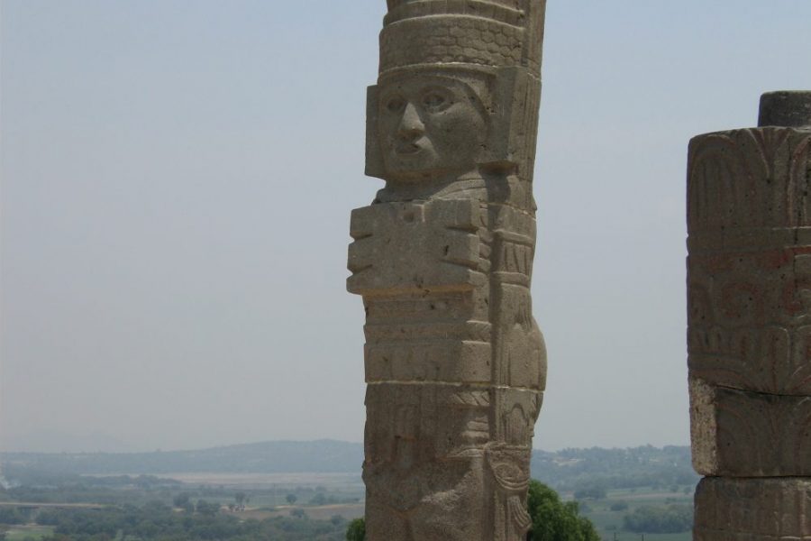 A man standing next to two large stone statues.