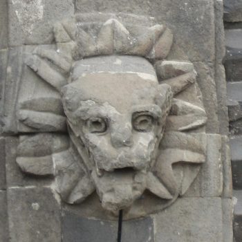 A stone face with sun rays on it's forehead.