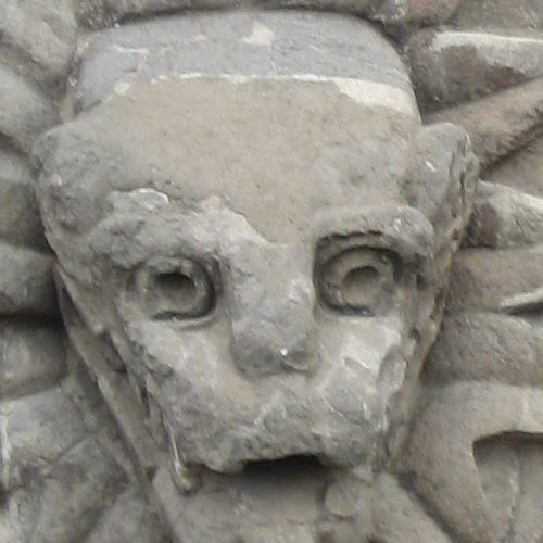 A stone sculpture of a face with long eyelashes.