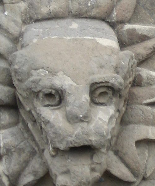 A stone sculpture of a face with long eyelashes.