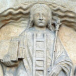 A statue of jesus holding a book and staff.