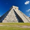 A large stone pyramid with grass in front of it.