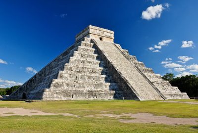 A large stone pyramid with grass in front of it.