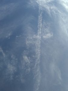 A cross shaped trail of smoke is seen in the sky.