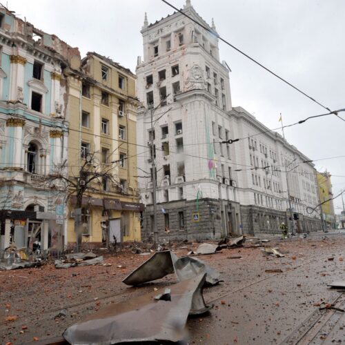 A street with buildings and rubble on the ground.