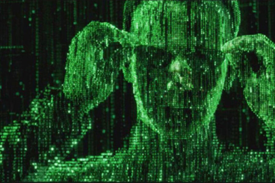 A man with green eyes and hair in front of a matrix style screen.