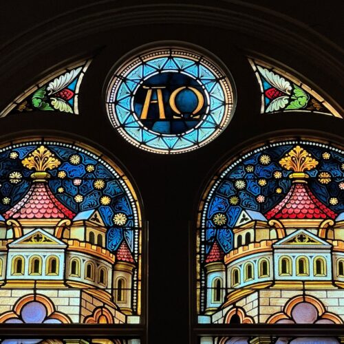 A stained glass window with the letters alpha omega on it.